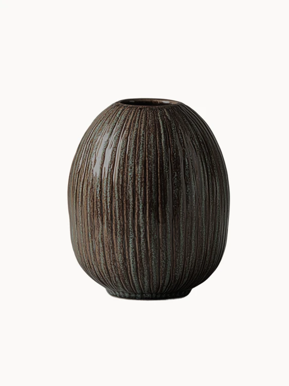 An oval, dark brown ceramic vase with a textured surface covered in vertical ribbed lines and subtle green speckled details, on a white background.