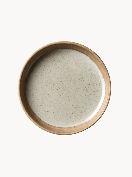 A top-down view of a round ceramic plate featuring a speckled, light grey glazed interior and a thick, unglazed natural terracotta rim.