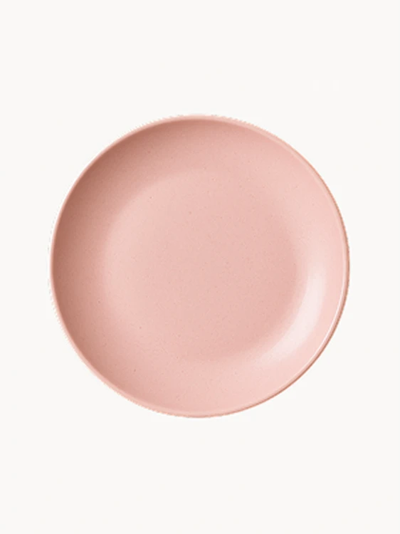 A top-down view of a matte, pastel pink ceramic plate.