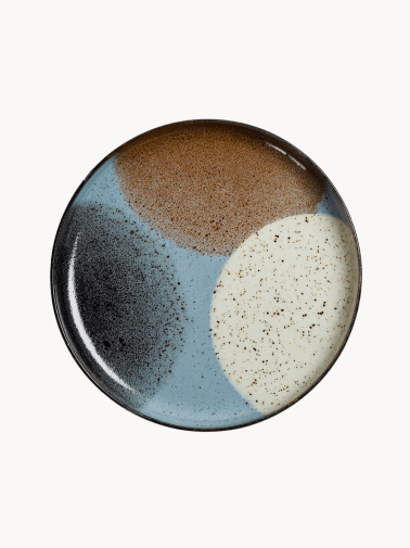 A top-down view on a large ceramic plate with a black rim features an abstract design of color blocks in brown, beige, light blue, and black.