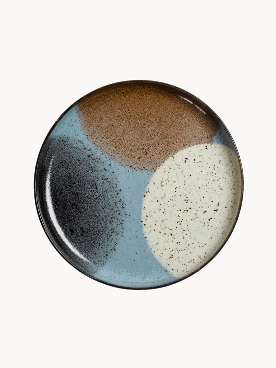 A top-down view on a large ceramic plate with a black rim features an abstract design of color blocks in brown, beige, light blue, and black.