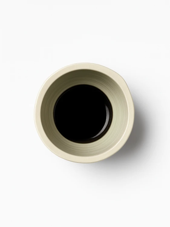 A top-down view on a pedestal ceramic bowl in a light cream color with a subtle crackle glaze and three horizontal black stripes around its middle.