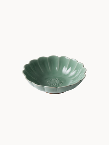 A small, sage green ceramic bowl designed in the shape of a blooming flower,  finished with a smooth glossy glaze, isolated on a plain white background.