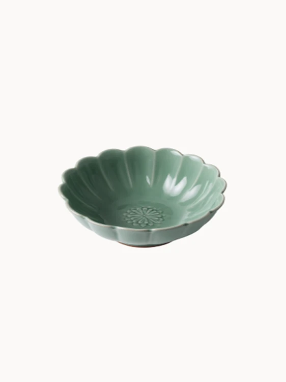 A small, sage green ceramic bowl designed in the shape of a blooming flower,  finished with a smooth glossy glaze, isolated on a plain white background.